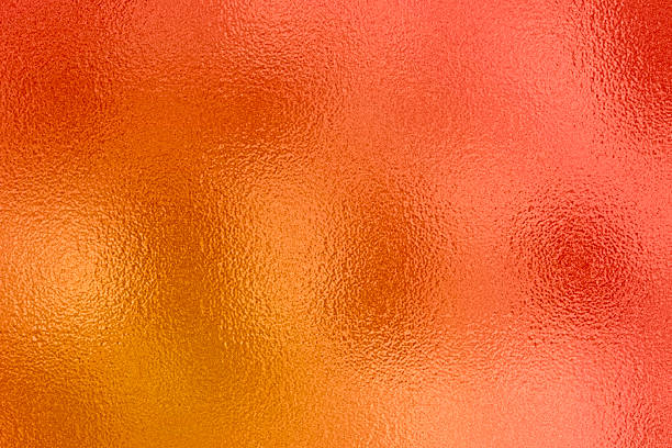 Abstract bright orange and red metallic foil texture background with shimmering reflective surface effect