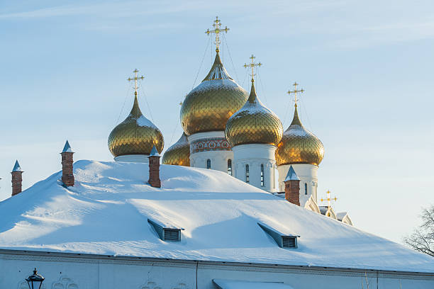 Orthodox church with golden domes rising above snow-covered trees under clear sky. Suitable for winter and religion concepts.