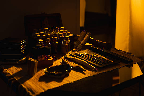 Glass jars and tools for incense and essential oils arranged on wooden table in warm light.