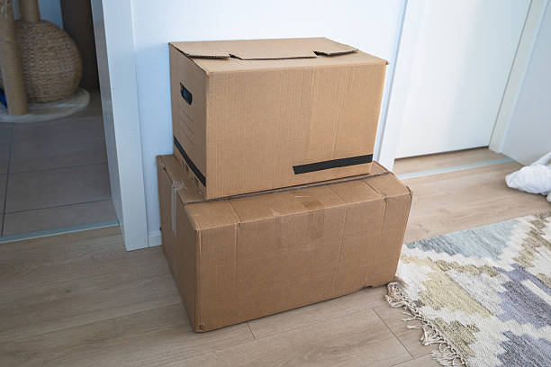 Cardboard moving boxes stacked on floor in minimalist home interior