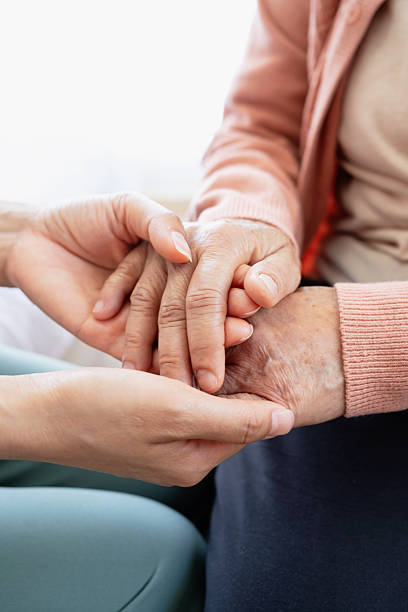 A woman holds hands and gives love to her elderly mother at home, creating bonding and happiness. love and care concept