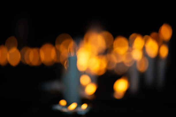Close-up of several white candles lit in a dark votive candle holder, symbolizing requests and gratitude in a religious setting.