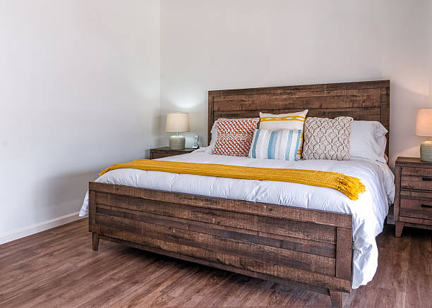 Modern rustic southwest bedroom with wood bed frame, nightstands, lamps, and decorative pillows. Side view.