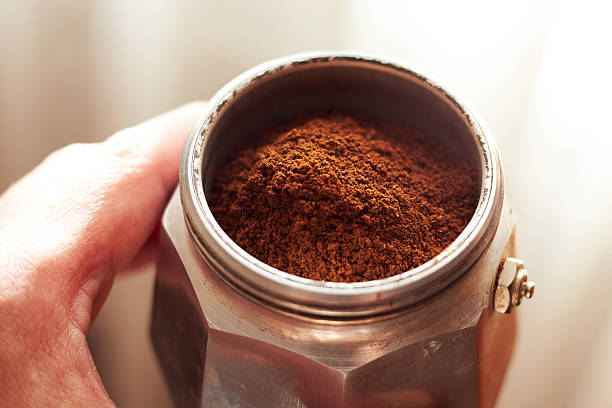 Funnel of a geyser coffee maker with ground coffee in hand