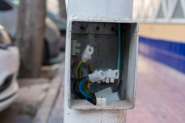 Open electrical junction box with exposed wires and connectors installed on outdoor pole. Concept of electrical maintenance, safety risk and infrastructure.