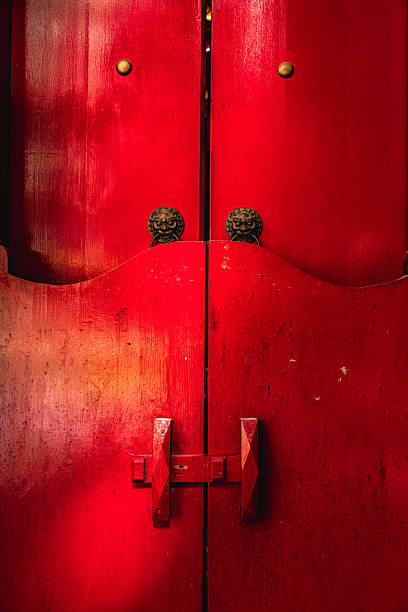 Red wooden doors featuring traditional lion head knockers and a rustic latch