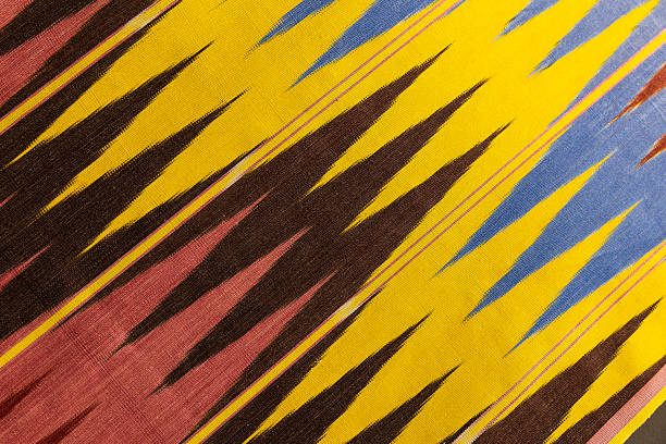 Vibrant ikat fabric featuring jagged stripes in yellow, blue, brown and red, showcasing a woven textile texture and traditional handcrafted pattern ideal for design, background and cultural projects