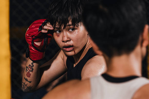 Young fighter prepares for the next move in a match inside the MMA match during a late evening.
