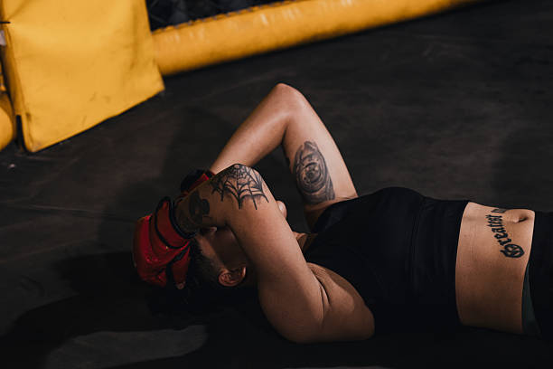 Woman resting on the ground in a MMA match after a knockout.