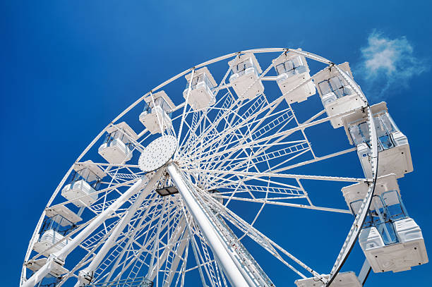 Low angle view of white ferris wheel cabins against clear deep blue sky in Nazare. The modern amusement ride contrasts with minimal background, ideal for leisure and summer travel themes. Nazare, Leiria District, Portugal, Southern Europe