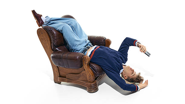 Young man lying upside down in armchair holding smartphone isolated on white. Concept of online learning break, social media use, home study lifestyle and modern student downtime.