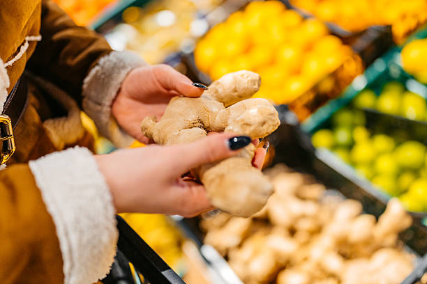 Young Woman Buying A Ginger Plant In A Supermarket