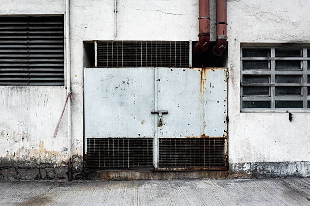 Gritty hong kong urban facade featuring a rusted metal gate and worn concrete wall