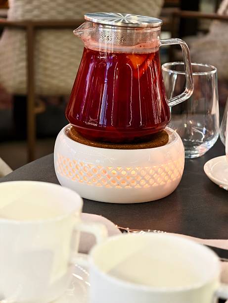 A glass teapot containing a vibrant, ruby-red berry tea