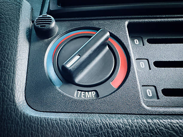 Close up macro shot of a retro automobile climate control rotary knob adjusted to the blue cooling zone for summer driving, set against a textured black leather interior.