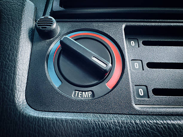 Close up macro shot of a retro automobile climate control rotary knob adjusted to the red heating zone for winter driving, set against a textured black leather interior.