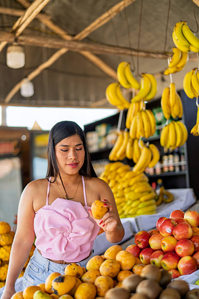 Young woman selecting mango at fresh fruit market stall