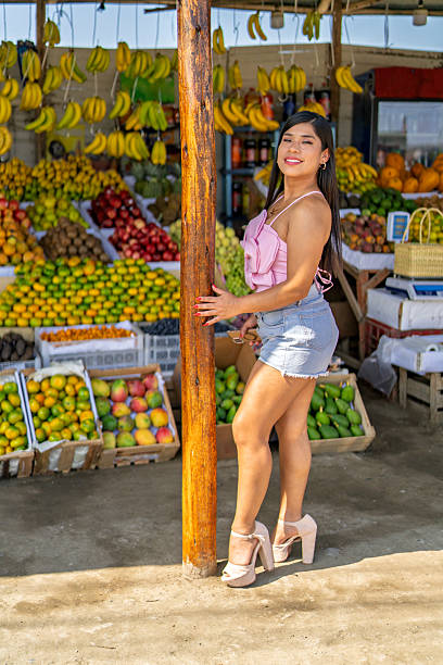 Smiling young woman posing at colorful fruit stall