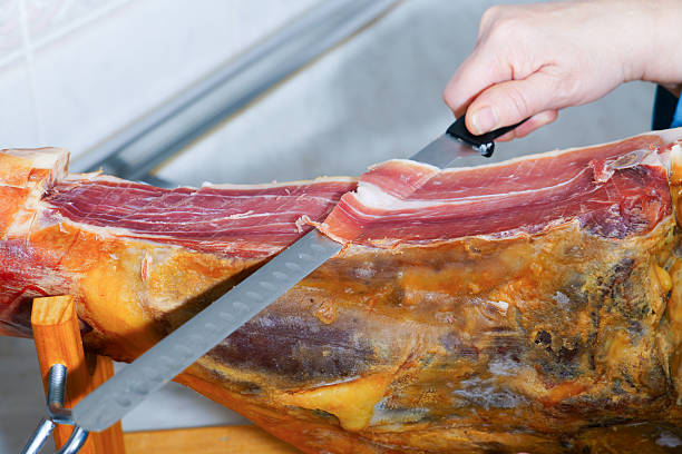 Hand slicing iberian cured ham on a ham holder stand