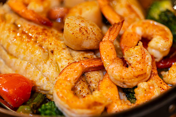 A Spanish-style seafood stew cooked in an exquisite copper pot, rich in prawns, scallops, and sea bass, accompanied by a variety of seasonal vegetables and drizzled with fine olive oil.