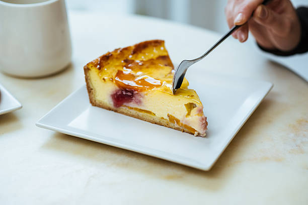 Enjoying a slice of cheesecake with fruit on a white plate at a cafe table
