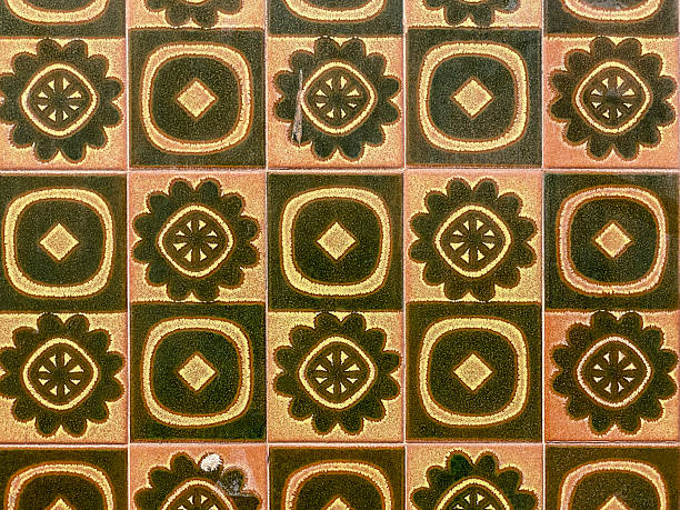 Front close-up view of a pattern of vintage inlaid tiles, featuring a flower within a circle and a geometric diamond pattern. These decorative ceramic tiles are known as azulejos, traditional in Spanish and Portuguese architecture.