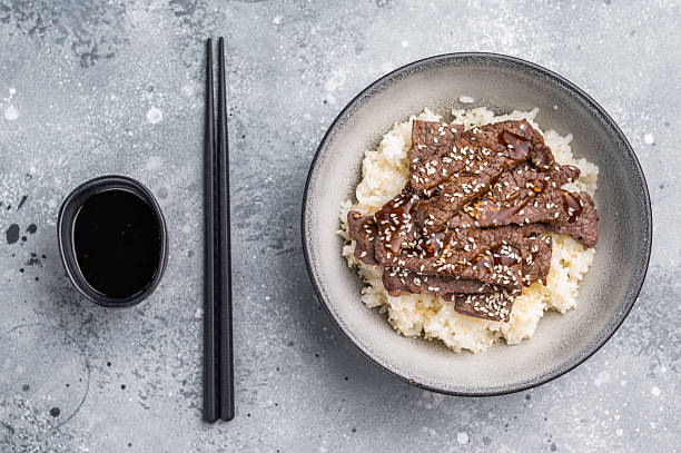 Delectable yakiniku feast, featuring a variety of marbled beef cuts and rice. A culinary journey that captures the essence of Japanese grilling traditions. grey background. top view