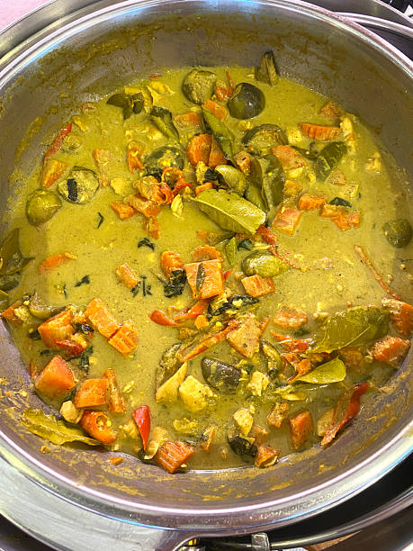 Chicken green curry with vegetables in a stainless steel pot, featuring vibrant colors and textures, top view close-up of a traditional Thai dish