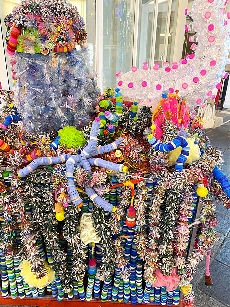 Colorful decorative arrangement created from recycled plastic items, showcasing various shapes and textures, displayed on a cart in a city environment