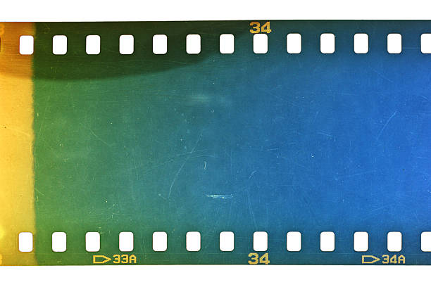 Dusty and grungy 35mm film texture or surface. Perforated scratched camera film isolated on white background.