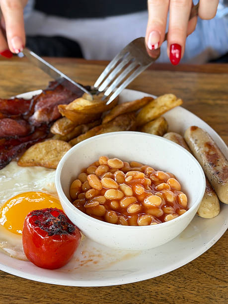 Image of person enjoying a hearty full English fried breakfast, juicy sausages, crispy bacon, fried eggs, grilled tomatoes, golden potato wedgesato wedges, baked beans,