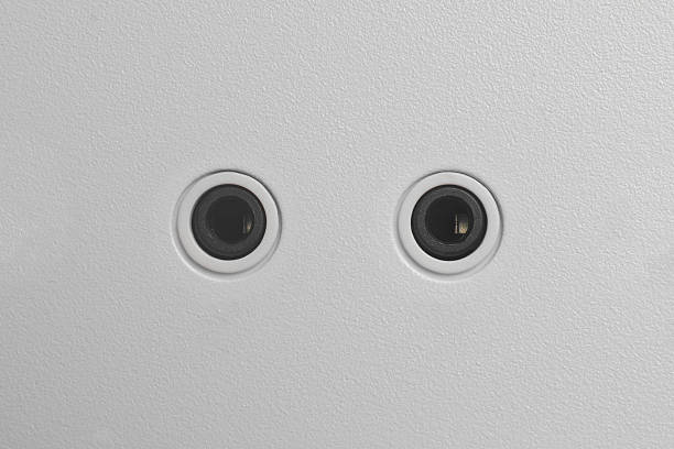black circular 3.5mm audio ports in textured white pc casing surface, minimalist electronic jack connectors, top view with copy space, hardware interface and connectivity concept