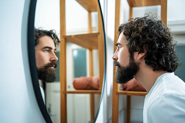 istock Thoughtful man standing in front of mirror in modern bathroom 2264047096
