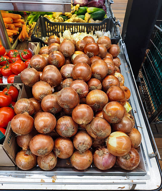 fresh brown onions with tomatoes and carrots in a grocery store.