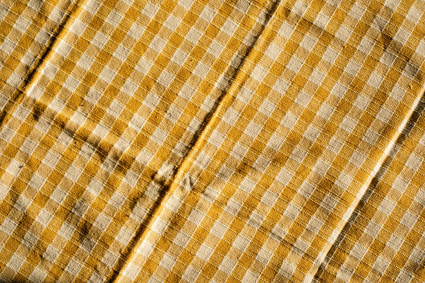 Yellow checkered fabric pattern with wrinkles in natural light.