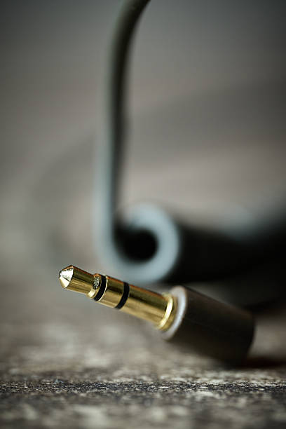 Macro shot of a gold-plated stereo mini-plug connector with a blurred cable on a textured surface