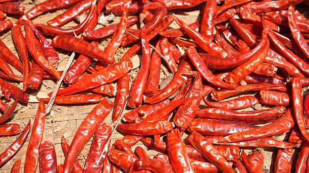 Dried red chili peppers spread out on wooden surface, showcasing their vibrant color and texture, perfect for culinary use or decoration