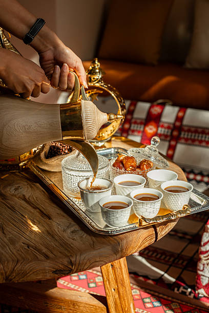 Pouring Arabic coffee in traditional sitting corner with dates and golden lantern on festive iftar table for ramadan fast breaking