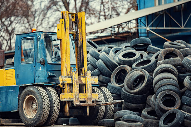 Industrial forklift preparing to move discarded rubber tires at a recycling facility
