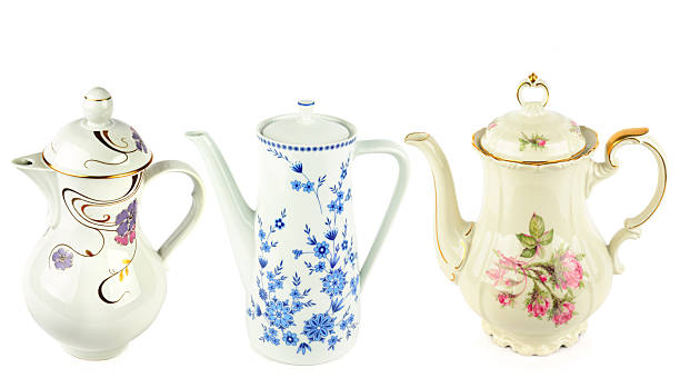 A collection of three elegant porcelain teapots featuring intricate floral motifs and gold trim. This high-quality isolated shot offers perfect copy space for vintage home decor branding.