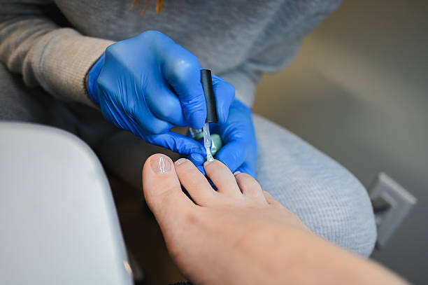 Beautician wearing blue gloves performing pedicure for client