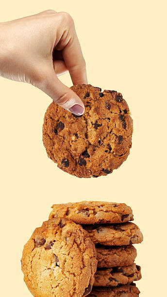 Hand takes a chocolate chip cookie from a tall stack of cookies for Easter.