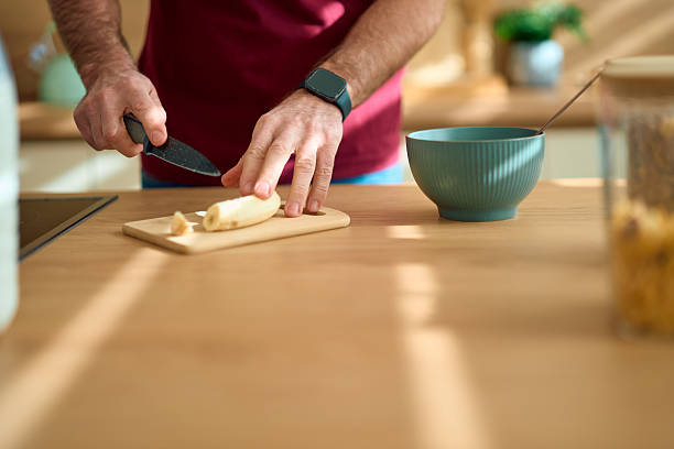 Man cutting banana for healthy breakfast in kitchen