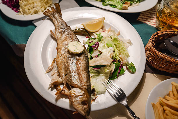 Grilled whole trout with fresh vegetables, on a white dish