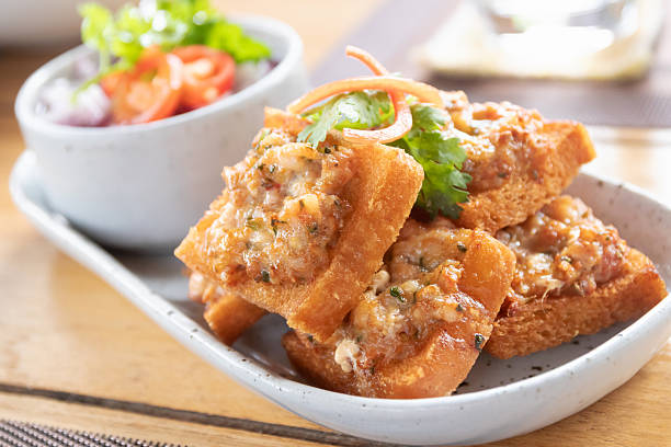 Crispy garlic bread topped with melted cheese and herb meat spread, served with fresh tomato salad for savory indulgence
