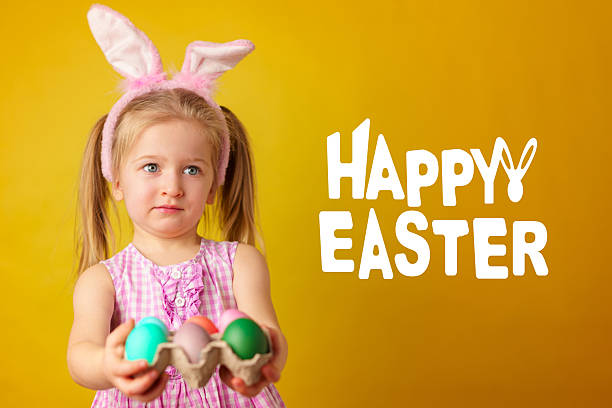 Child holds colorful Easter eggs and wears bunny ears for a fun holiday activity