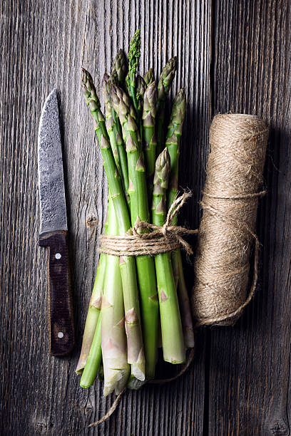 Bunch of green asparagus spears with knife and kitchen twine