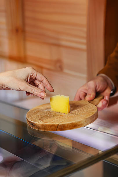 Aged cheese round wooden board, artisan dairy shop tasting sampling customer, master cheesemaker delicatessen traditional craftsmanship retail store