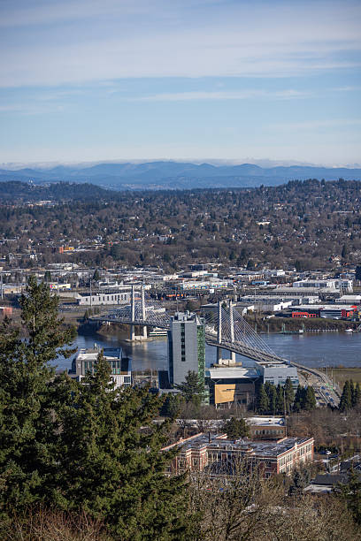 A city view from a high vantage point with a bridge in the foreground. The city is bustling with activity and has a mix of residential and commercial buildings