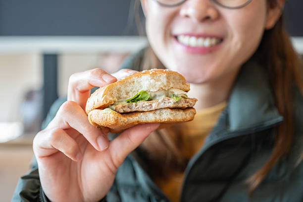 Cropped shot view of young Asian woman holding a hamburger after bite it.